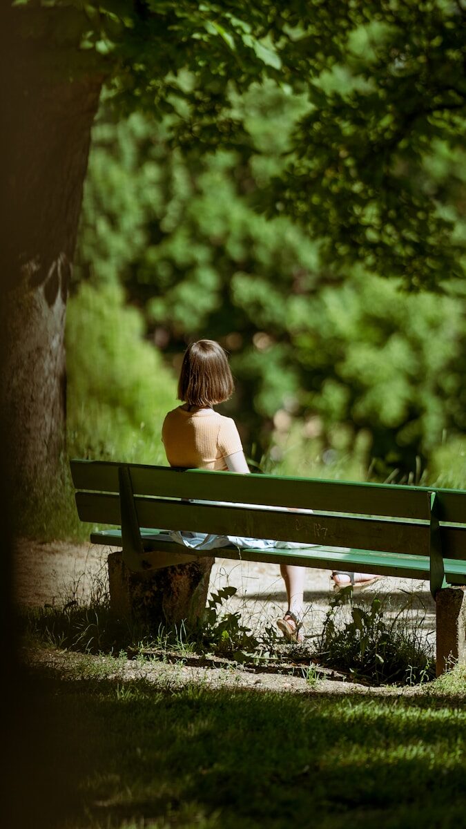 a woman sitting on a bench in a park